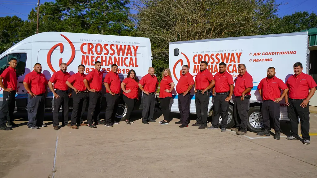The Crossway Mechanical crew in red uniform shirts lined up in front of two branded box trucks
