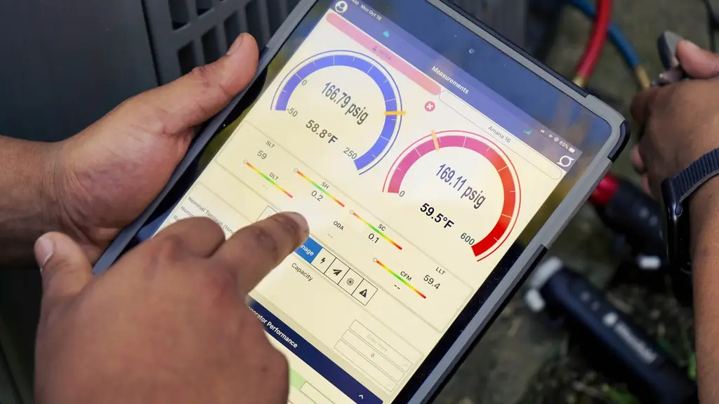 Technician's hands on a tablet running the iManifold app: 166.79 psig at 58.8°F on the blue gauge, 169.11 psig at 59.5°F on the red, superheat 0.2 and subcooling 0.1, refrigerant hoses behind